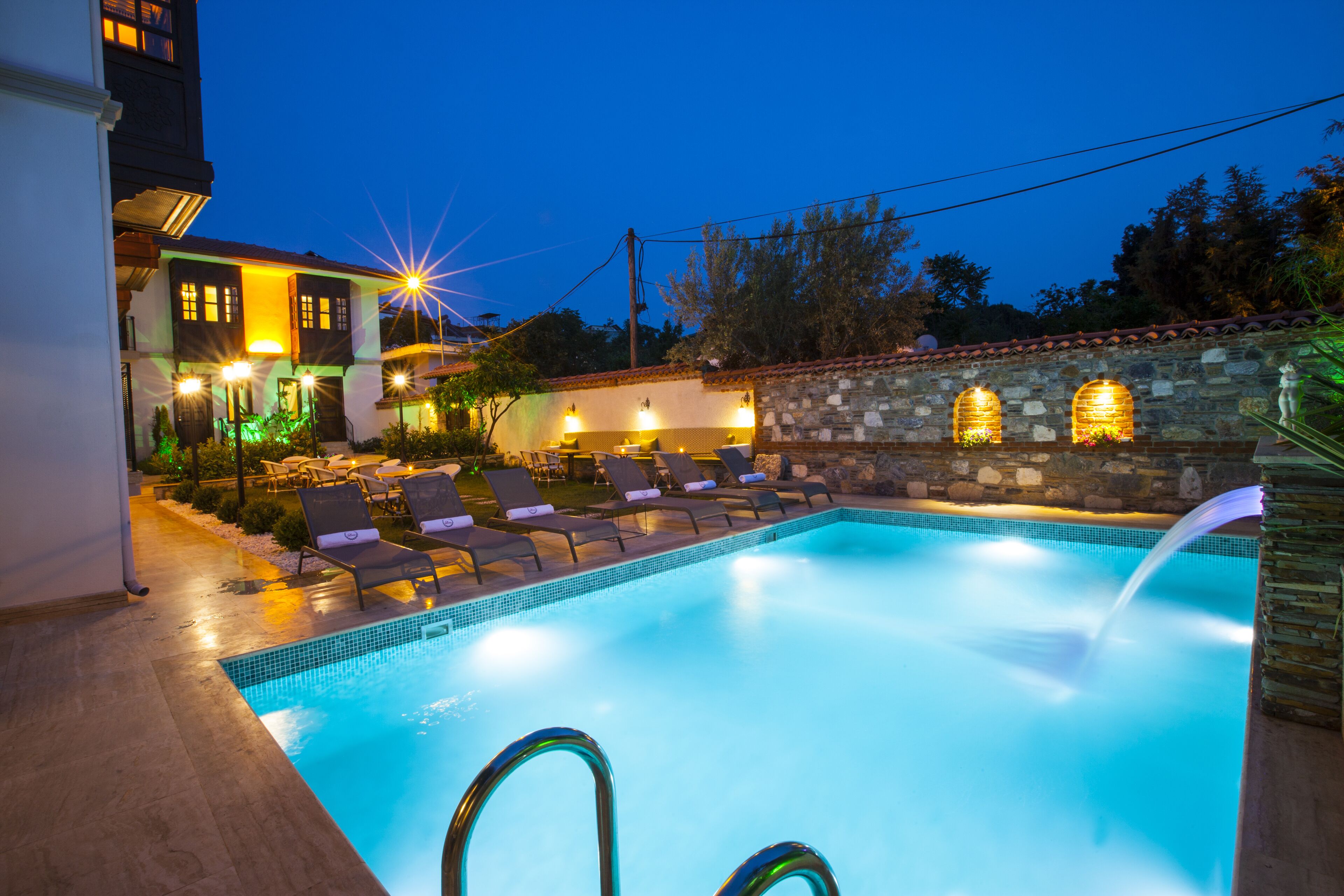 A swimming pool with lounge chairs and a stone wall.