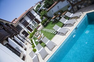 Una piscina al aire libre, sombrillas, sillones reclinables de piscina