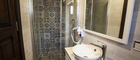 A bathroom with a glass shower enclosure, a white sink, and a mirror above it.