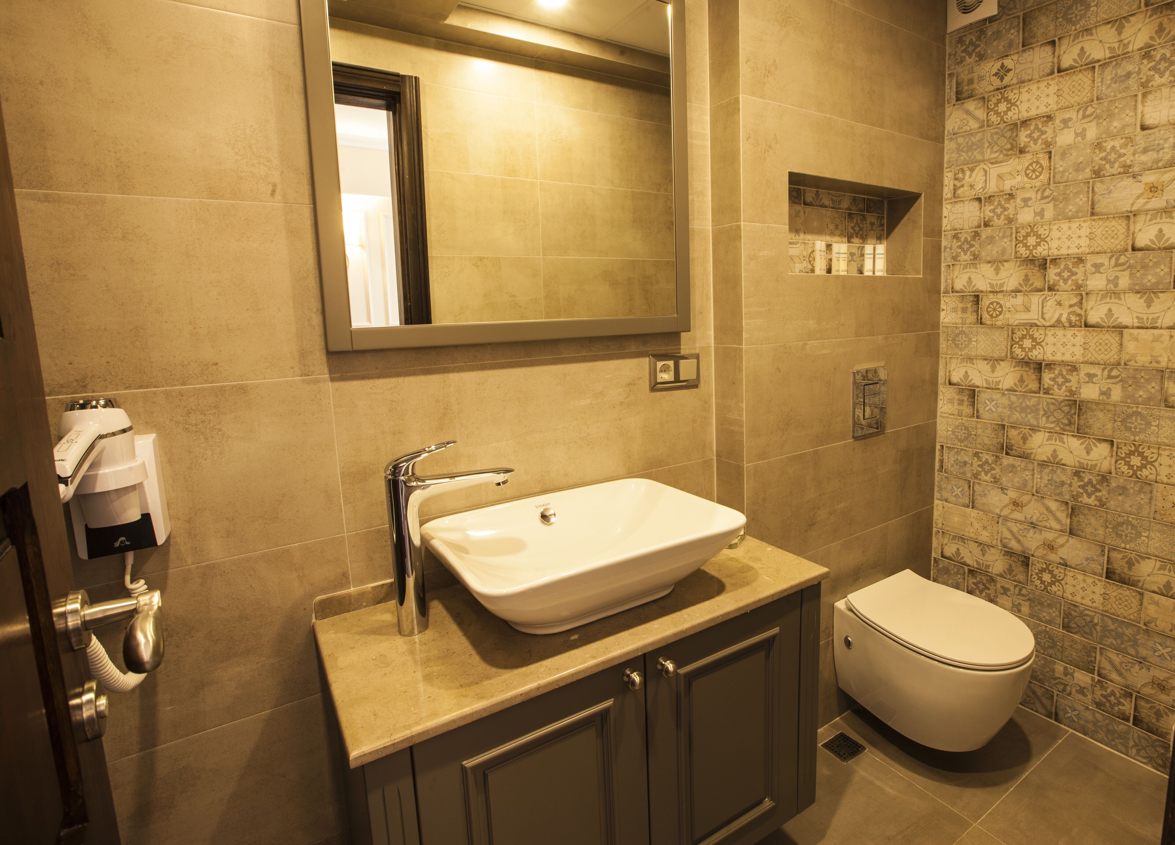 Un baño con un espejo grande, un lavamanos, un inodoro y una zona de ducha.