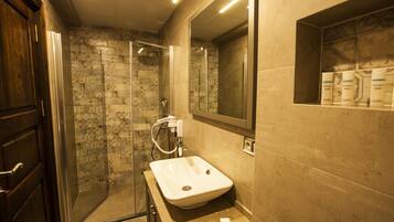 A bathroom with a glass shower enclosure, a sink, and a mirror.
