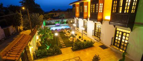 A courtyard with a swimming pool, outdoor seating, and a well-lit garden area.