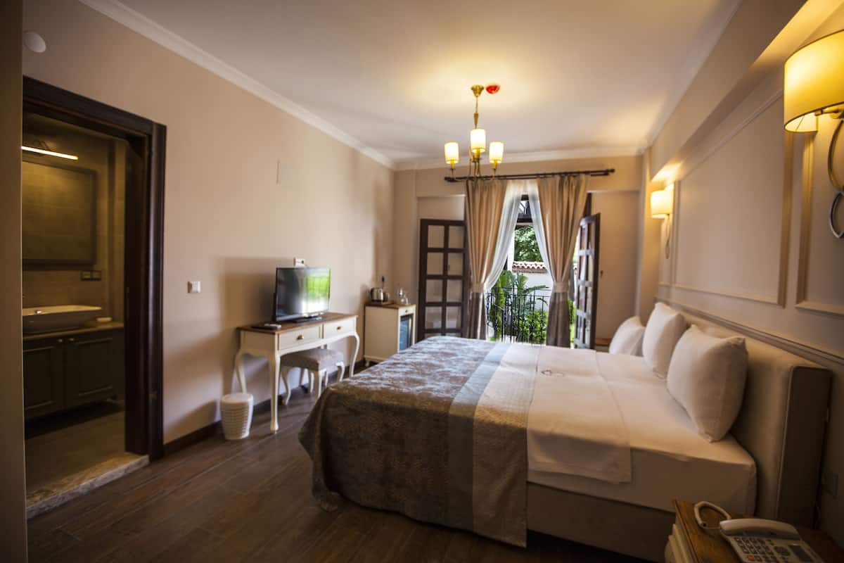 A hotel room with a bed, desk, television, and a view of the outdoors.