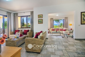 A spacious living area with wicker furniture, a glass coffee table, and a view of the outdoors. - Exceptional Large Villa, Free Heated Pool 1 NOV - 15 Jan, Privacy,prime Location (Pegeia)