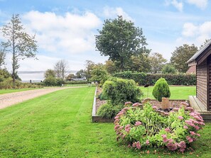 Un jardín bien cuidado con césped, parterres de flores y una estructura de madera.