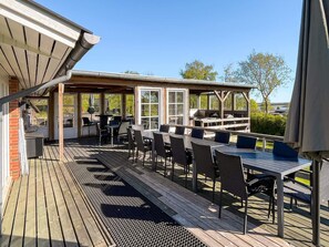 An outdoor patio with a covered seating area, a grill, and a view of the surrounding landscape.