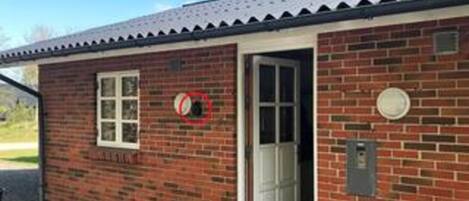 A brick building with a white door, a window, and a circular sign on the wall.