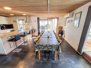 Una cocina moderna con barra, una larga mesa de comedor con sillas y vistas al exterior.