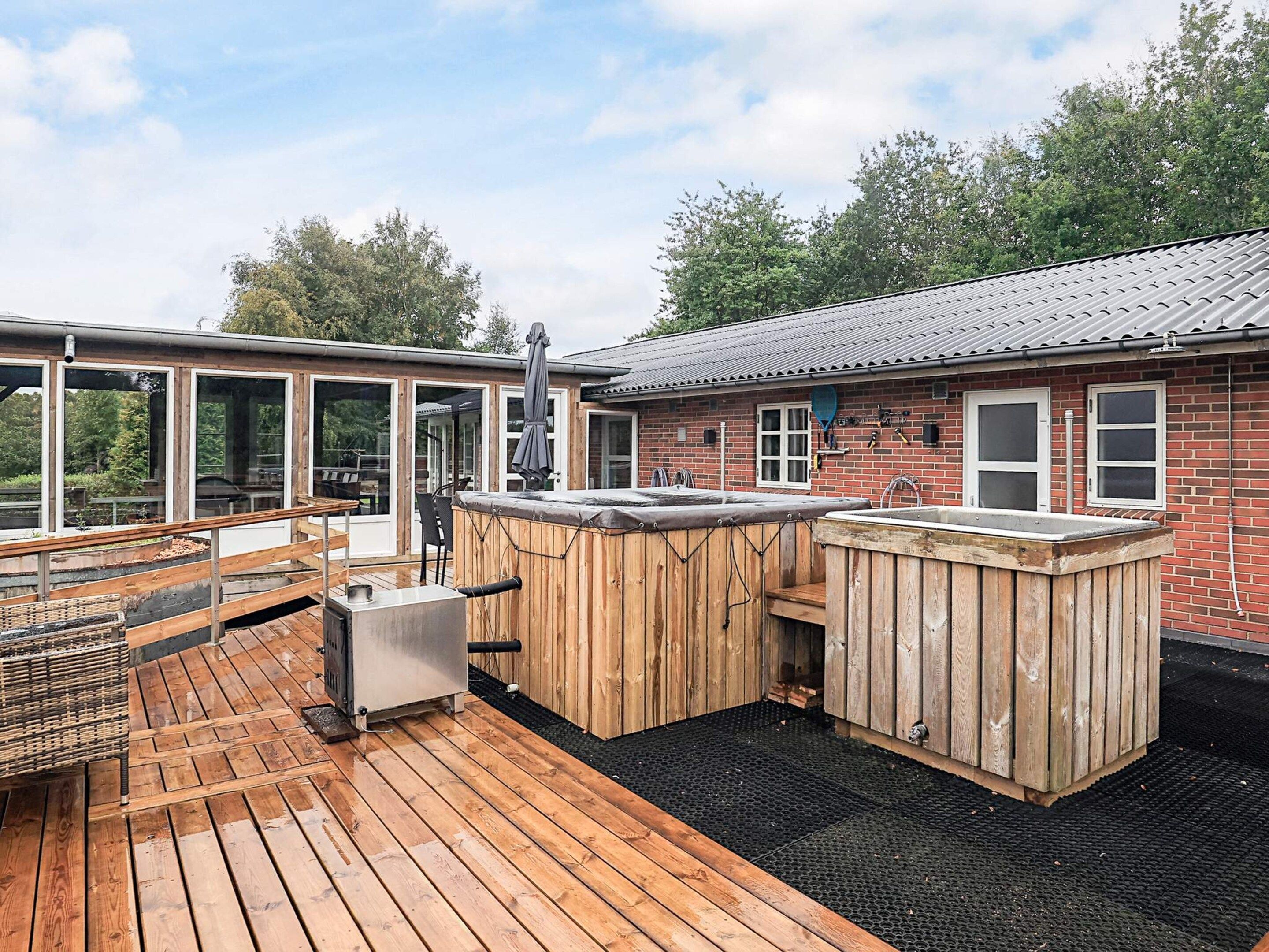 A deck with a hot tub, outdoor seating, and a barbecue grill.