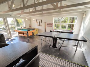 A room with a pool table, foosball table, and ping pong table, with large windows and a view of the outdoors. - 5 Star Holiday Home in Roslev (Roslev)