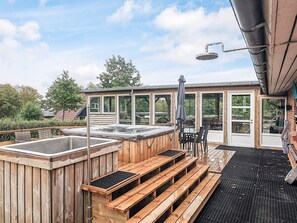 A wooden deck with a hot tub, outdoor seating, and a covered area with a table and chairs. - 5 Star Holiday Home in Roslev (Roslev)