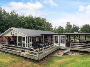 Un espacio al aire libre cubierto con una parrilla, asientos y una terraza de madera.