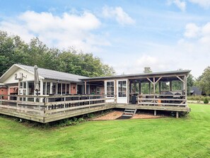 A two-story building with a covered patio and outdoor seating area. - 5 Star Holiday Home in Roslev (Roslev)