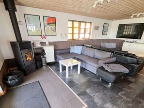 A modern living room with a sofa, a coffee table, a fireplace, and a television.
