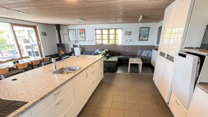 A kitchen with a granite countertop, white cabinets, a built-in oven, and a dining area with a sofa and chairs. - 5 Star Holiday Home in Roslev (Roslev)
