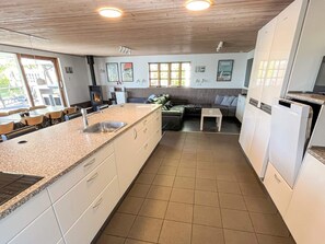 A kitchen with a granite countertop, white cabinets, a built-in oven, and a dining area with a sofa and chairs.