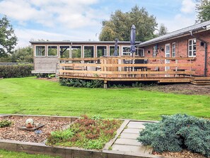 A two-story house with a deck, a garden with plants and a decorative stone, and a clear sky. - 5 Star Holiday Home in Roslev (Roslev)