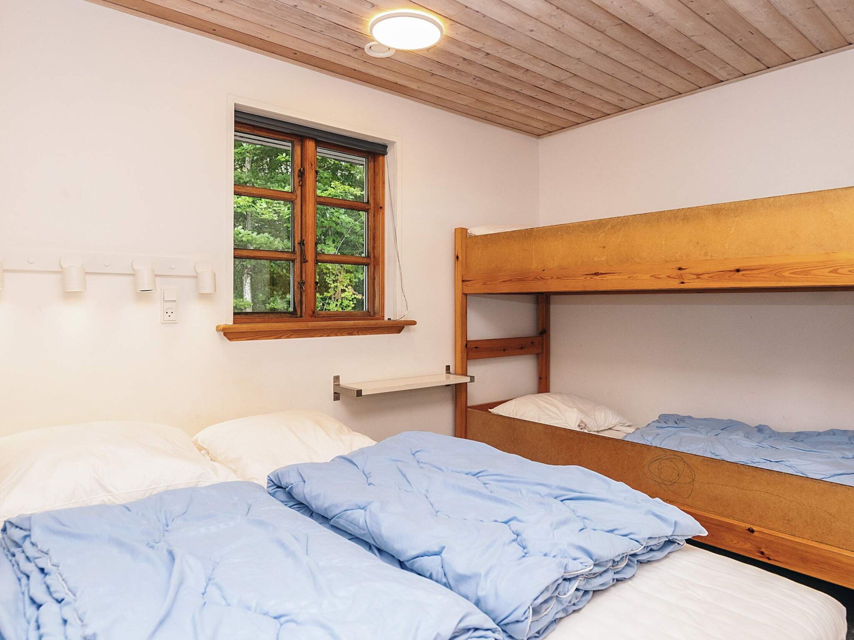 A bunk bed room with a window, a shelf, and a ceiling light.