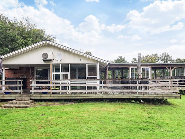 A building with a covered patio area, outdoor seating, and a grassy lawn. - 5 Star Holiday Home in Roslev (Roslev)