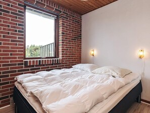 A bedroom with a brick wall, a window, a bed with white bedding, and two wall-mounted lights. - 7 Person Holiday Home in Frostrup (Frøstrup)