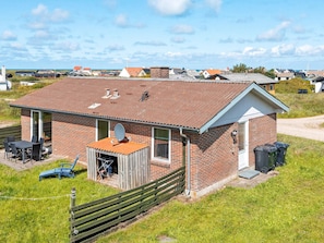 A single-story brick house with a sloped roof, a small porch, and a satellite dish. - 7 Person Holiday Home in Frostrup (Frøstrup)