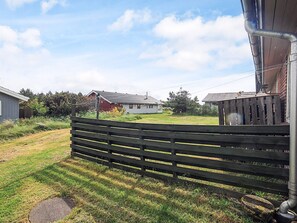 A rural property with a grassy yard, a wooden fence, and a house with a red roof. - 7 Person Holiday Home in Frostrup (Frøstrup)