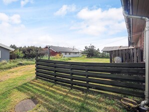 A rural setting with a wooden fence, a grassy area, and a red barn in the background.