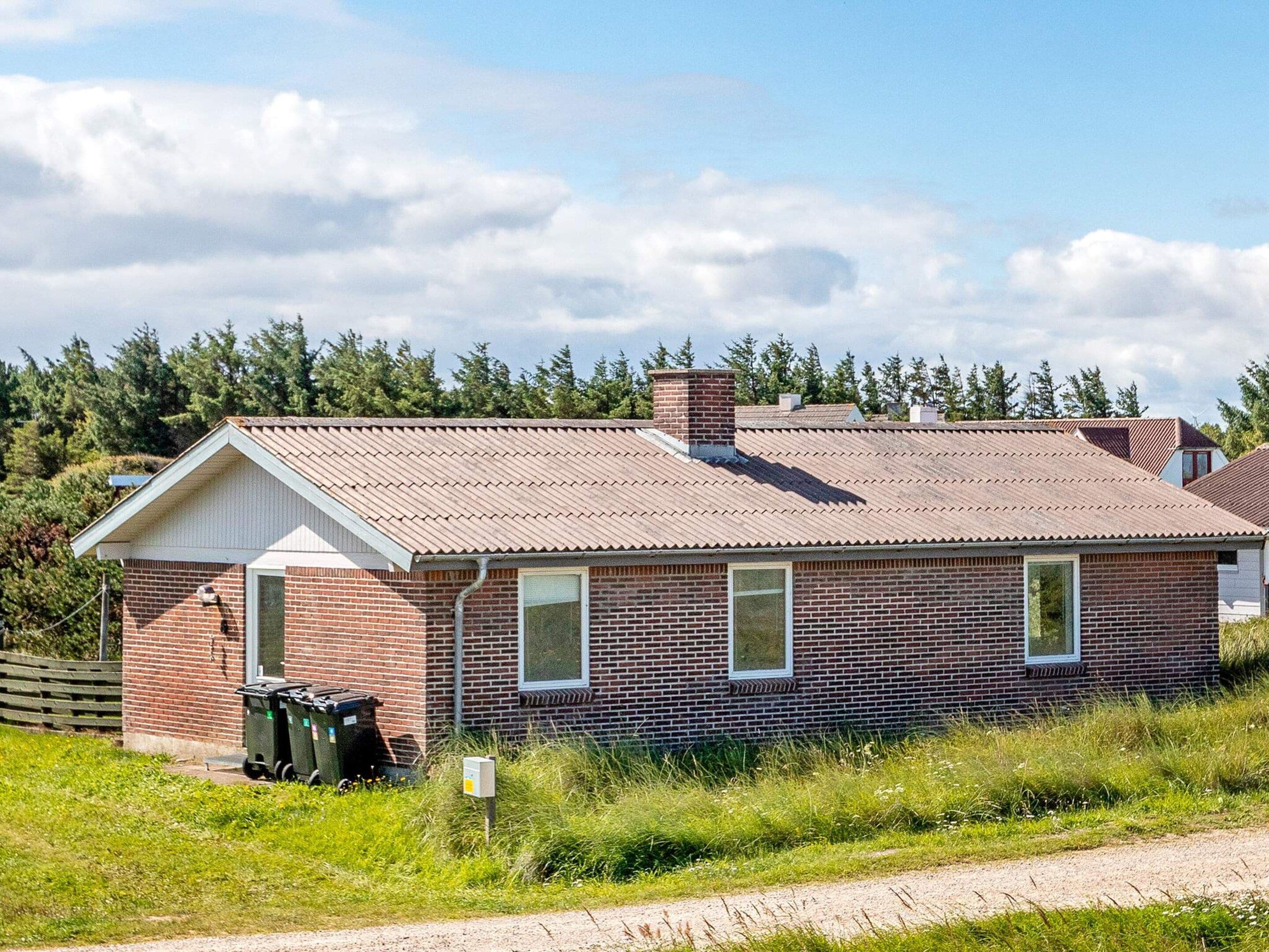 A single-story brick building with a gabled roof, a front door, and a small window.