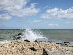 A beach with pebbles, waves, and a clear sky. - 6 Person Holiday Home in Albaek (Jerup)