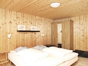 A wooden-paneled room with two beds, a shelf with artwork, and a door leading to another room. - 6 Person Holiday Home in Albaek (Jerup)