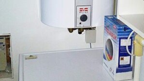 A room with a washing machine, a control panel, and a door.