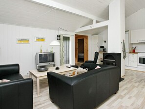 A modern living room with a sofa, a television, a dining table, and a kitchen area with cabinets and a microwave. - 6 Person Holiday Home in Albaek (Jerup)