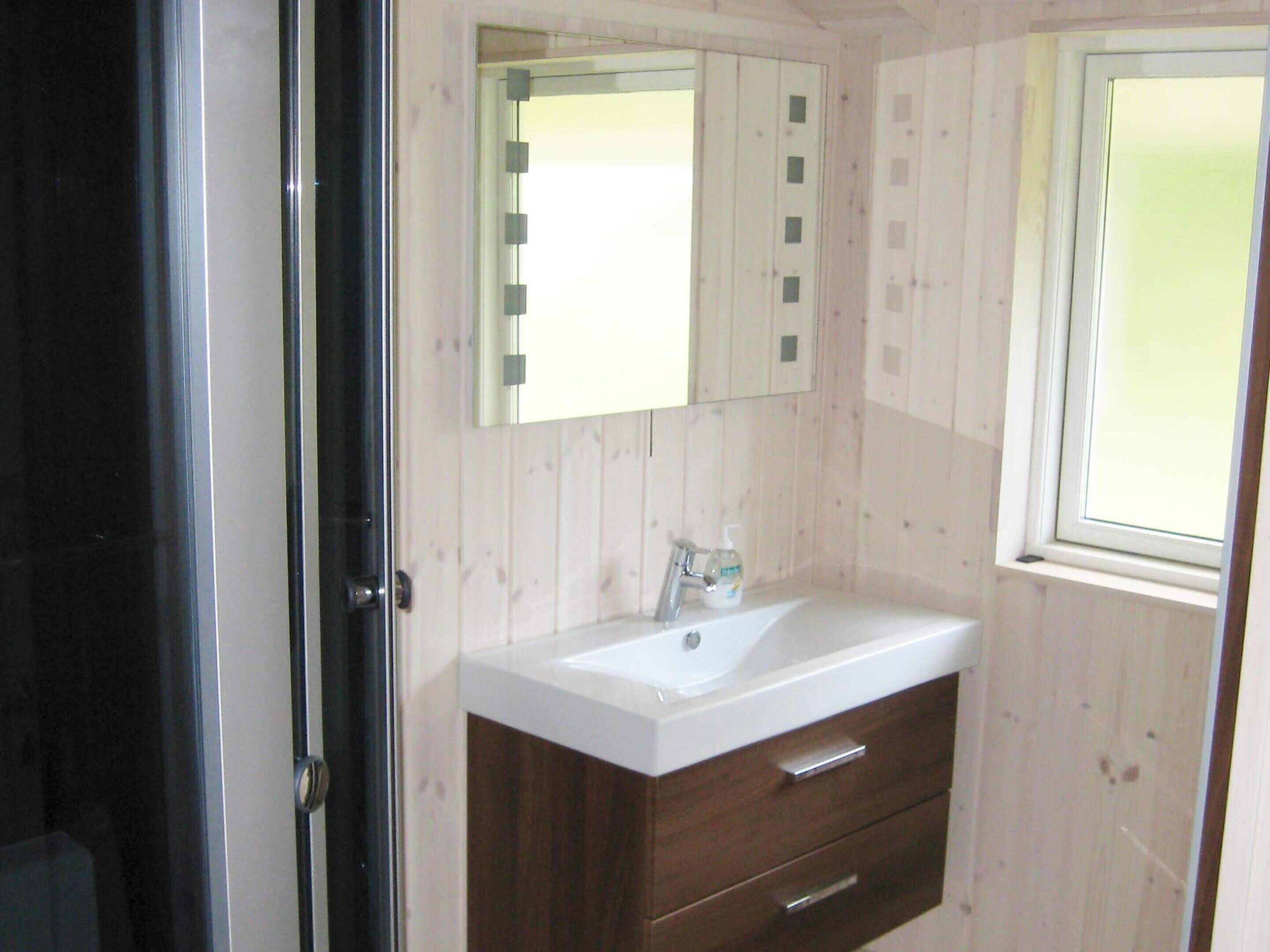 A bathroom with a white sink, a mirror, and a window.