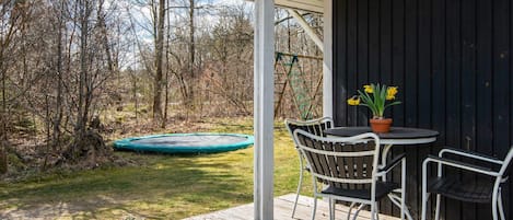 A covered outdoor area with a table and chairs, a trampoline, and a wooden deck.