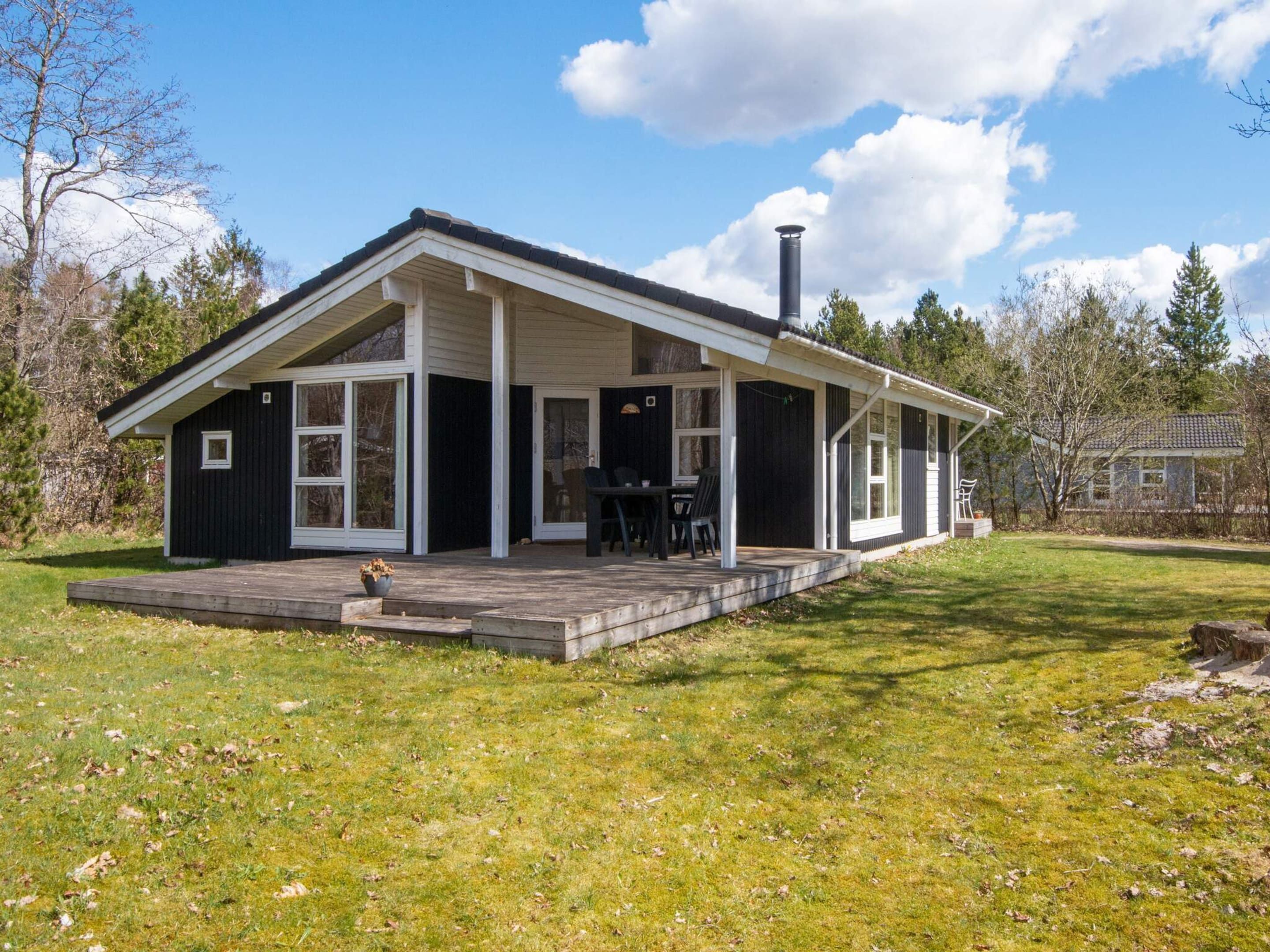 Eenlaags huis met een overdekte veranda, schoorsteen en een klein terras.