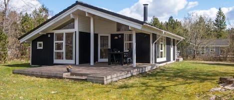 A single-story house with a covered porch, a chimney, and a small deck area.