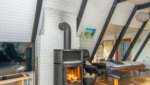 A cozy room with a wood-burning stove, a comfortable seating area with a sofa and armchair, and a wooden floor. - Seaside Spa Retreat - By Traum Ferienwohnungen (Haderslev)