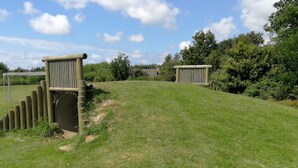 A grassy field with a wooden structure and a metal gate.