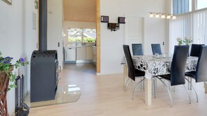 A modern kitchen with a central island, a dining area with a table and chairs, and a large window providing natural light.