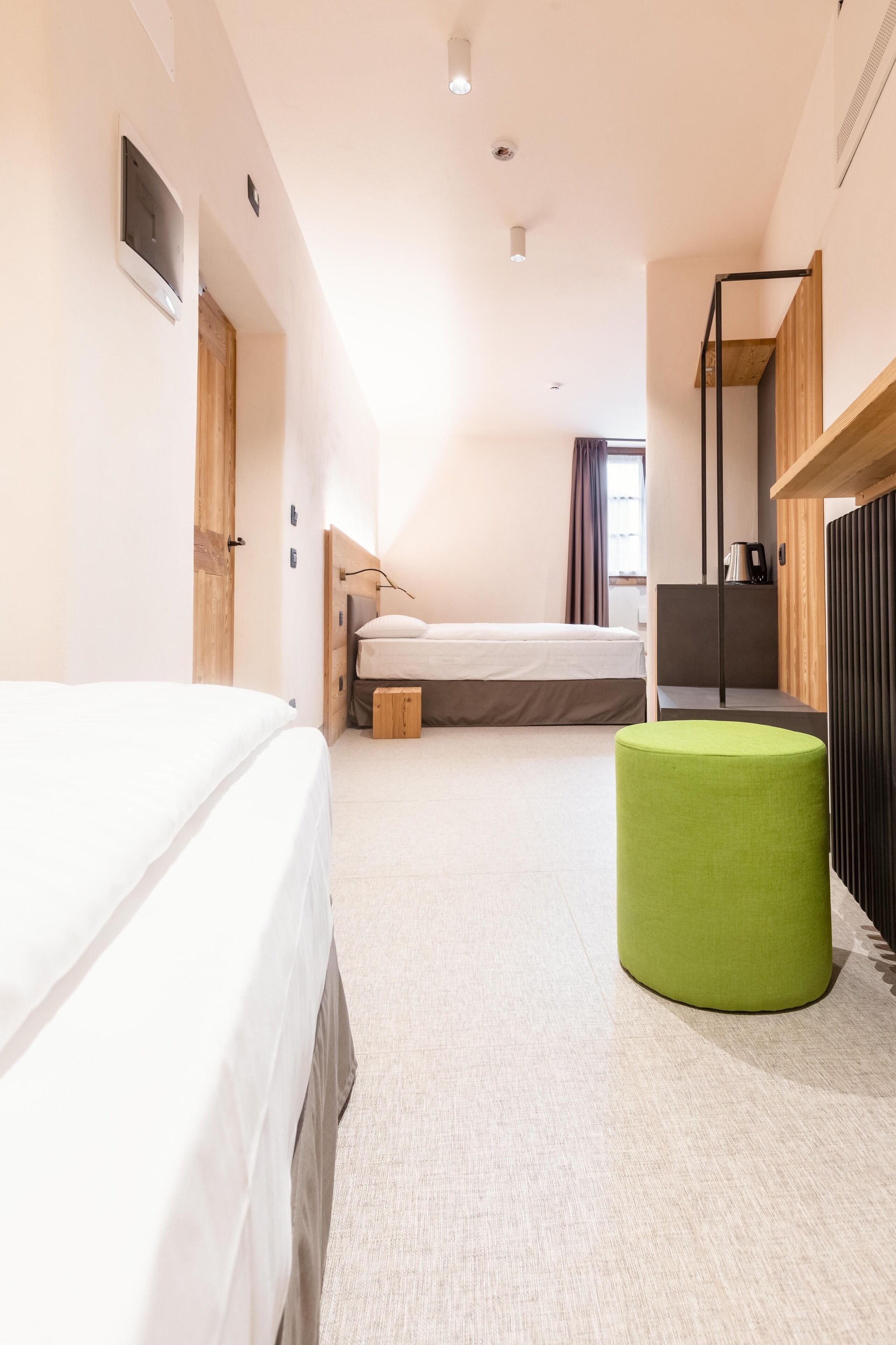Una habitación de hotel moderna con una cama grande, un reposapiés verde, un escritorio y vistas a la ciudad.