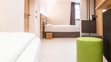 Una habitación de hotel moderna con una cama grande, un reposapiés verde, un escritorio y vistas a la ciudad.