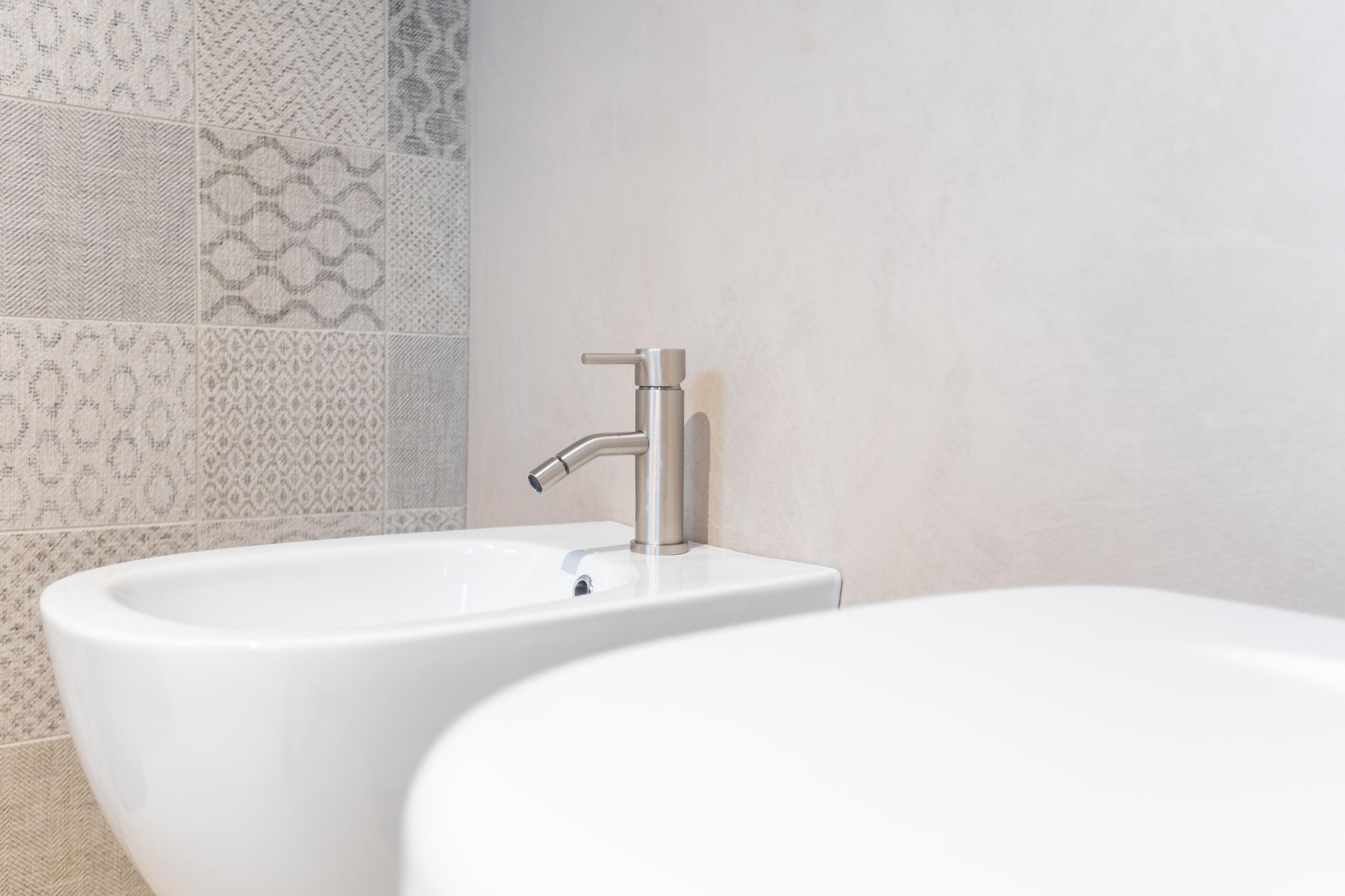 A bathroom with two sinks and a bathtub, tiled walls with a geometric pattern.