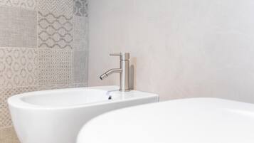 A bathroom with two sinks and a bathtub, tiled walls with a geometric pattern.