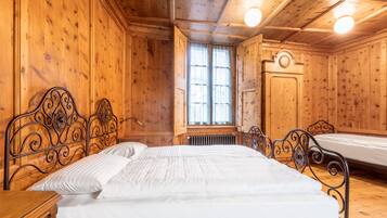 A wooden room with a large bed, a smaller bed, and a window.