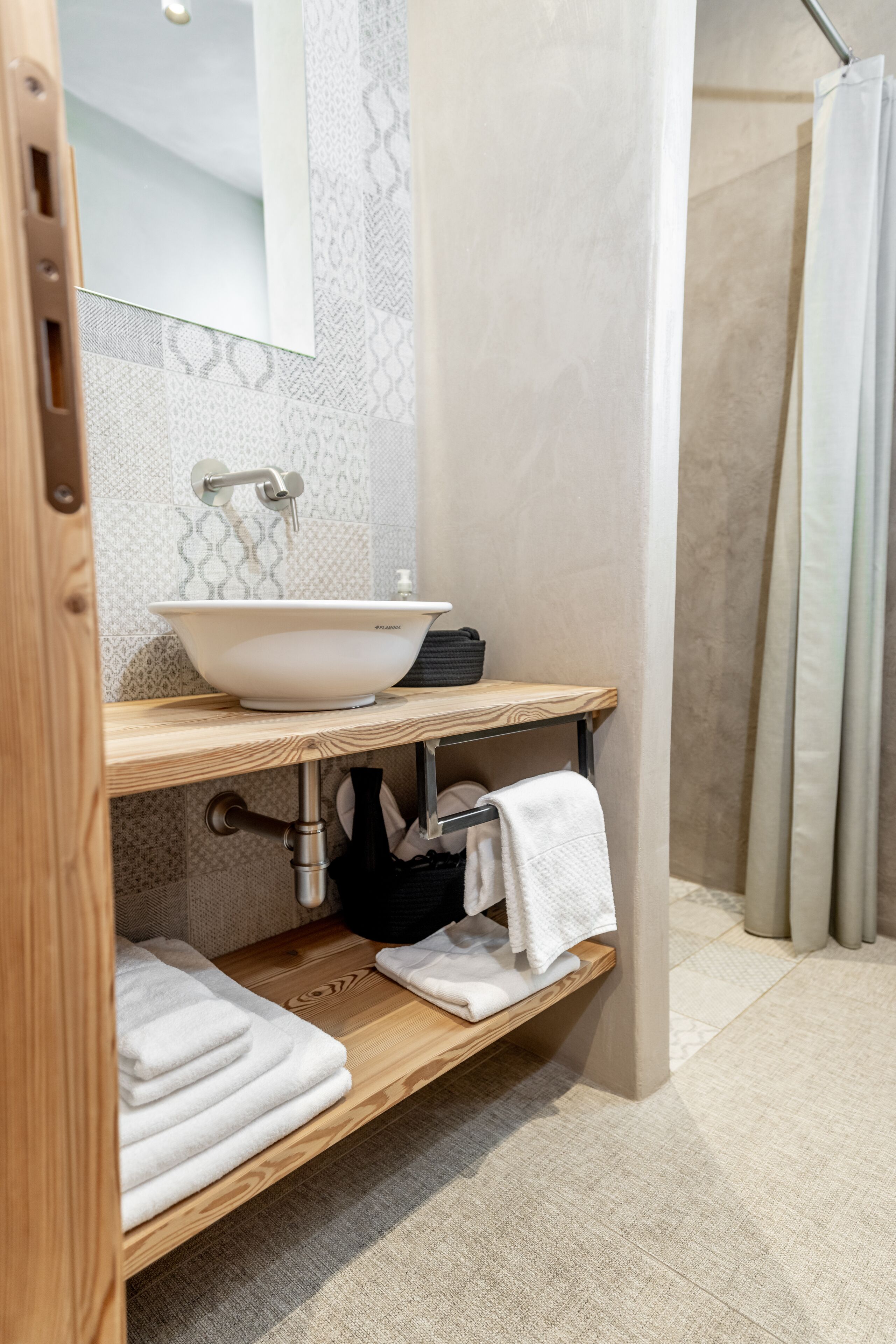 Un baño con tocador de madera, un lavamanos blanco y un perchero para toallas.