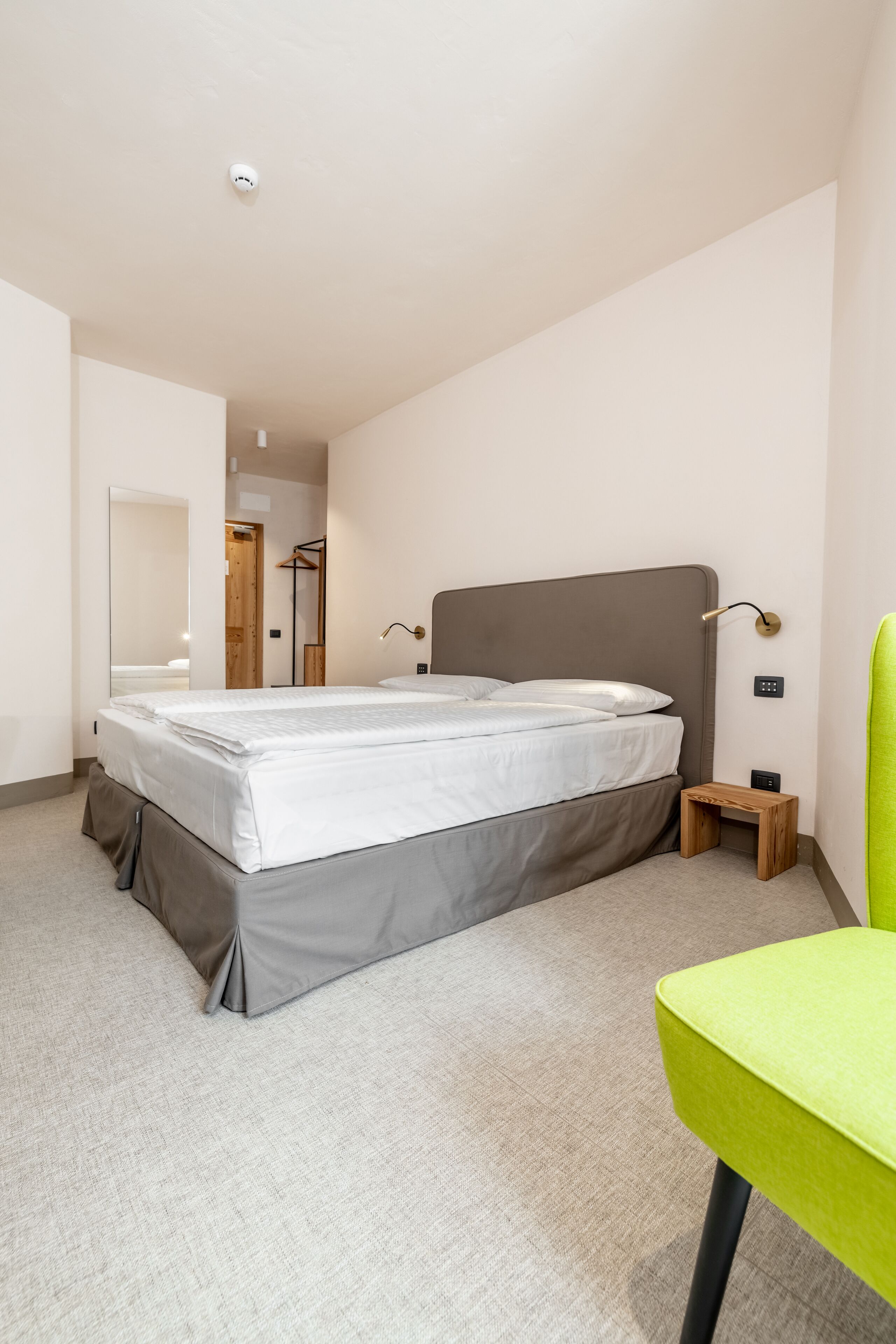 Une chambre moderne avec un grand lit, une table de chevet, une chaise et un miroir.