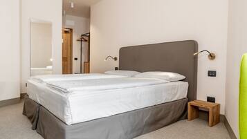 Une chambre moderne avec un grand lit, une table de chevet, une chaise et un miroir.