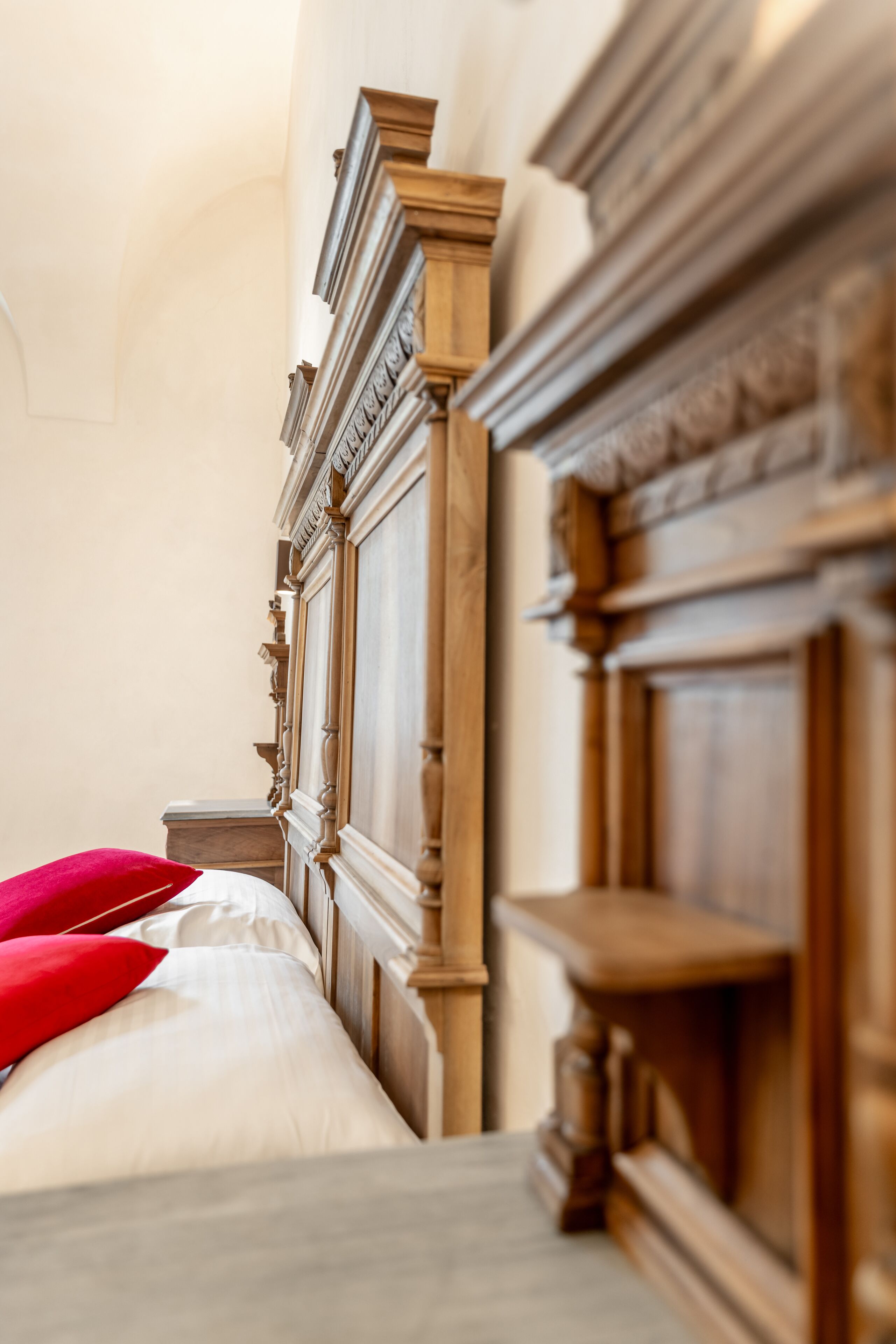 Une chambre à coucher avec une tête de lit en bois, un lit avec une literie blanche et des oreillers rouges, et une table de chevet en bois.