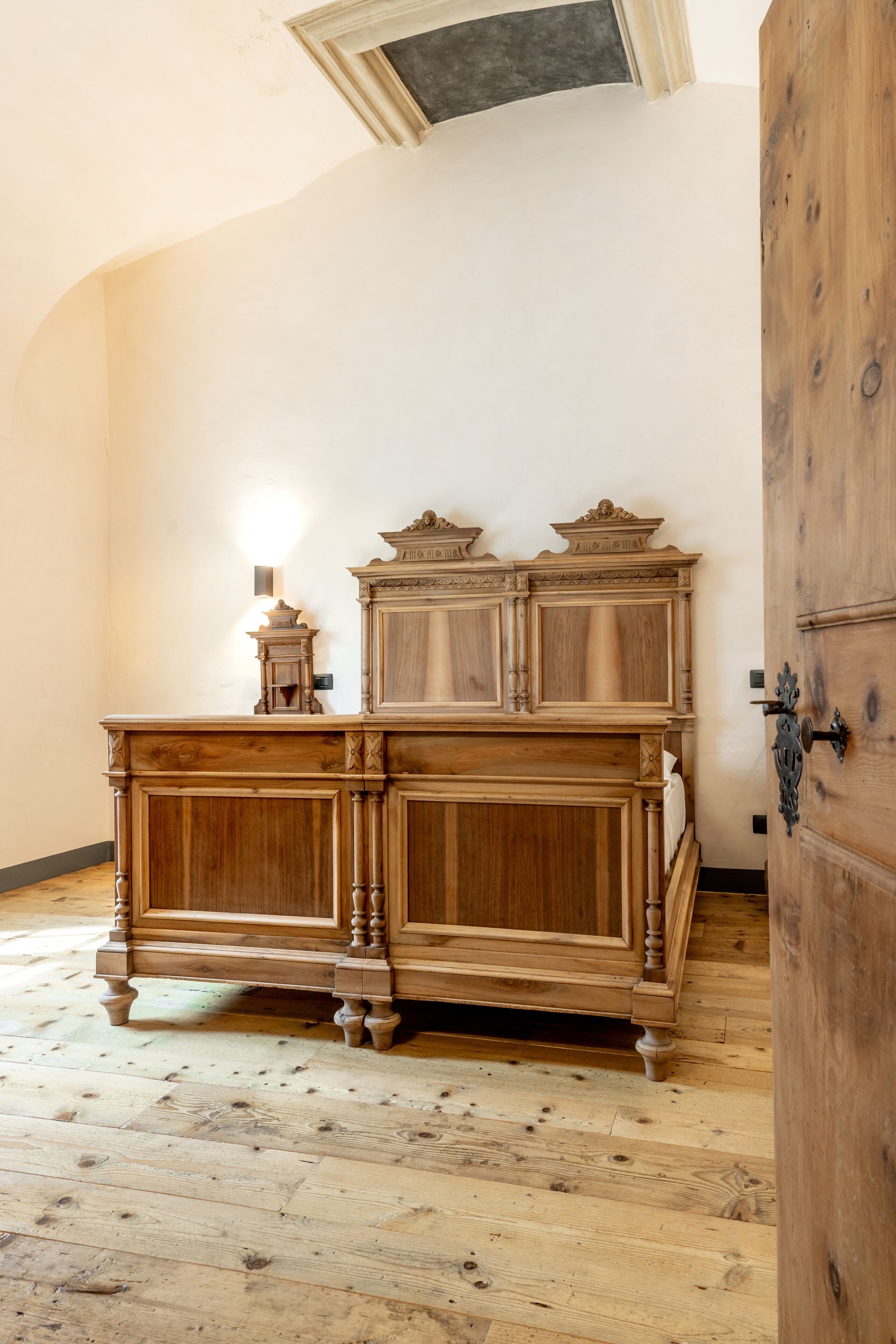 A wooden dresser with intricate carvings, a small wall-mounted light, and a wooden door with a metal handle.