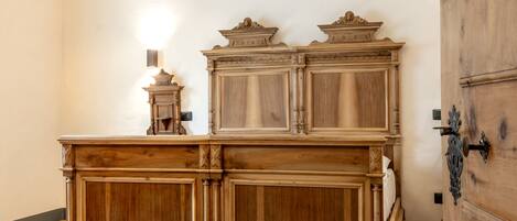 A wooden dresser with intricate carvings, a small wall-mounted light, and a wooden door with a metal handle.